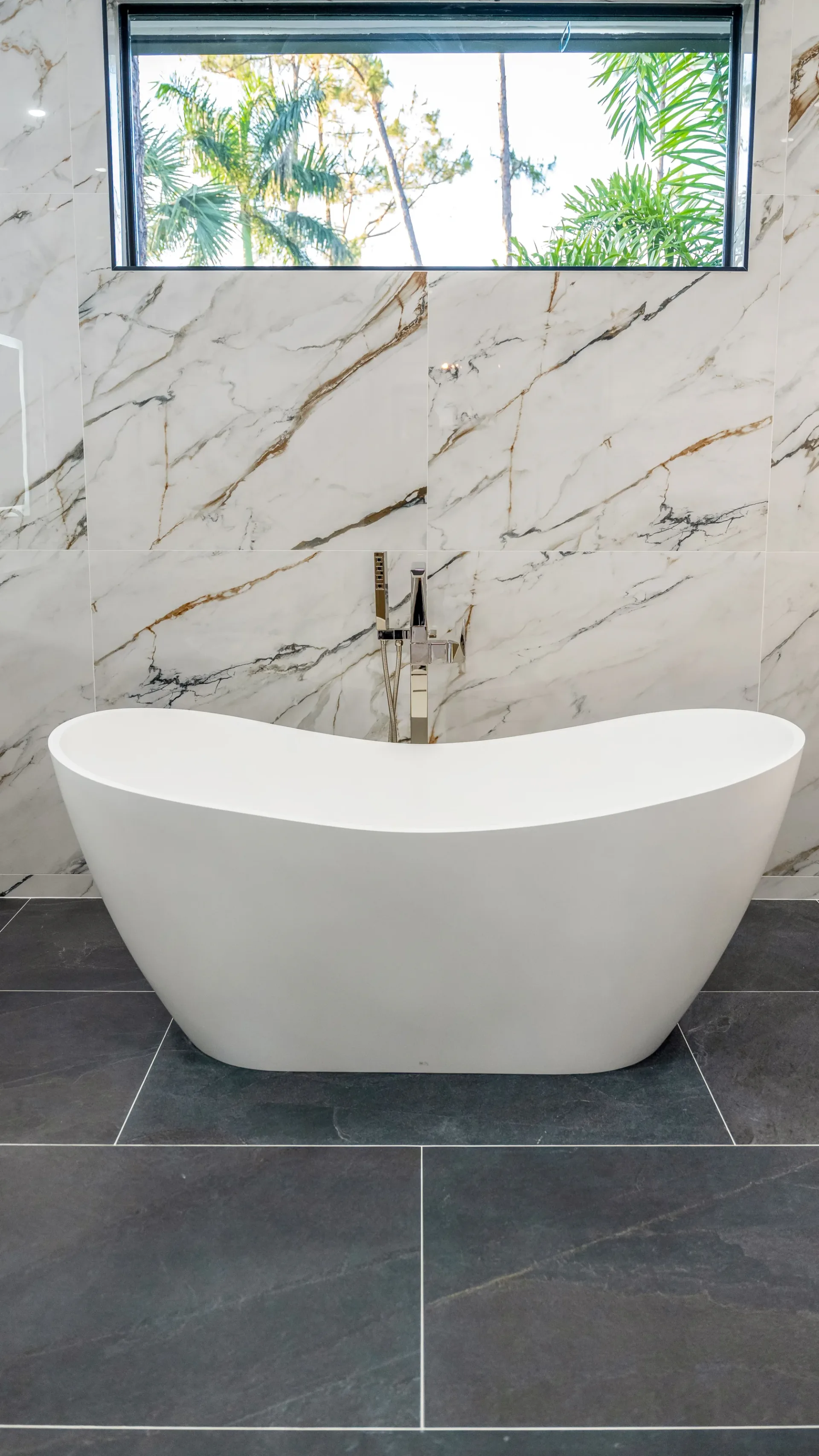 Luxury spa bathroom with marble tiles and designer fixtures in The Emerald Mediterranean revival home at 210 16th Ave NE, Naples FL by XL Homes custom home builder