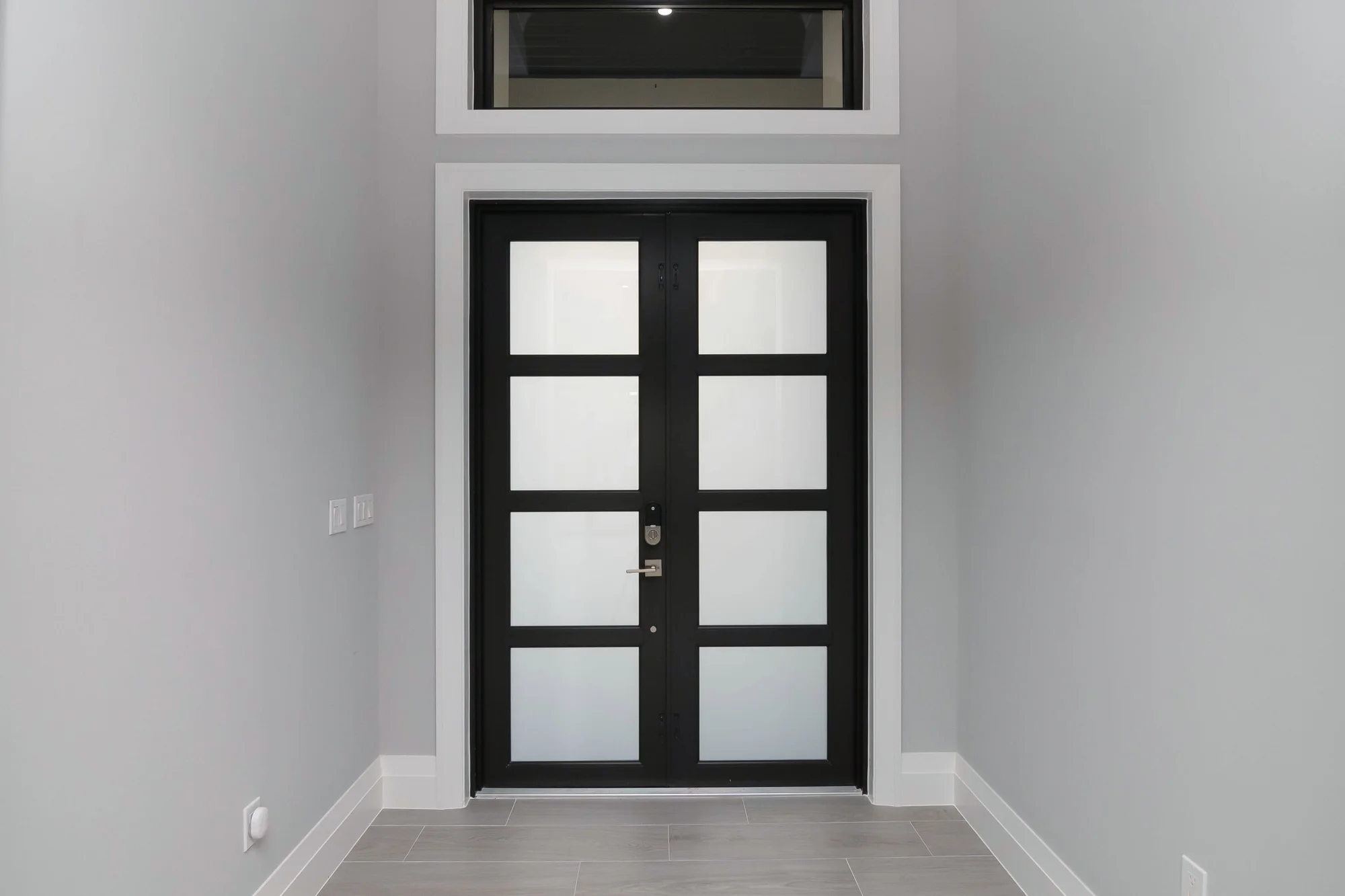 Grand entryway with statement door and decorative tile in The Oasis coastal contemporary home at 760 15th St SW, Naples FL by XL Homes custom home builder