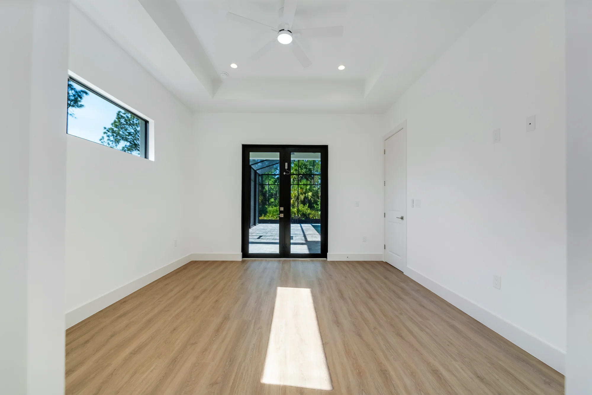 Spacious master suite with tray ceiling and custom millwork in The Sapphire contemporary waterfront home at 619 22nd St SE, Naples FL by XL Homes custom home builder