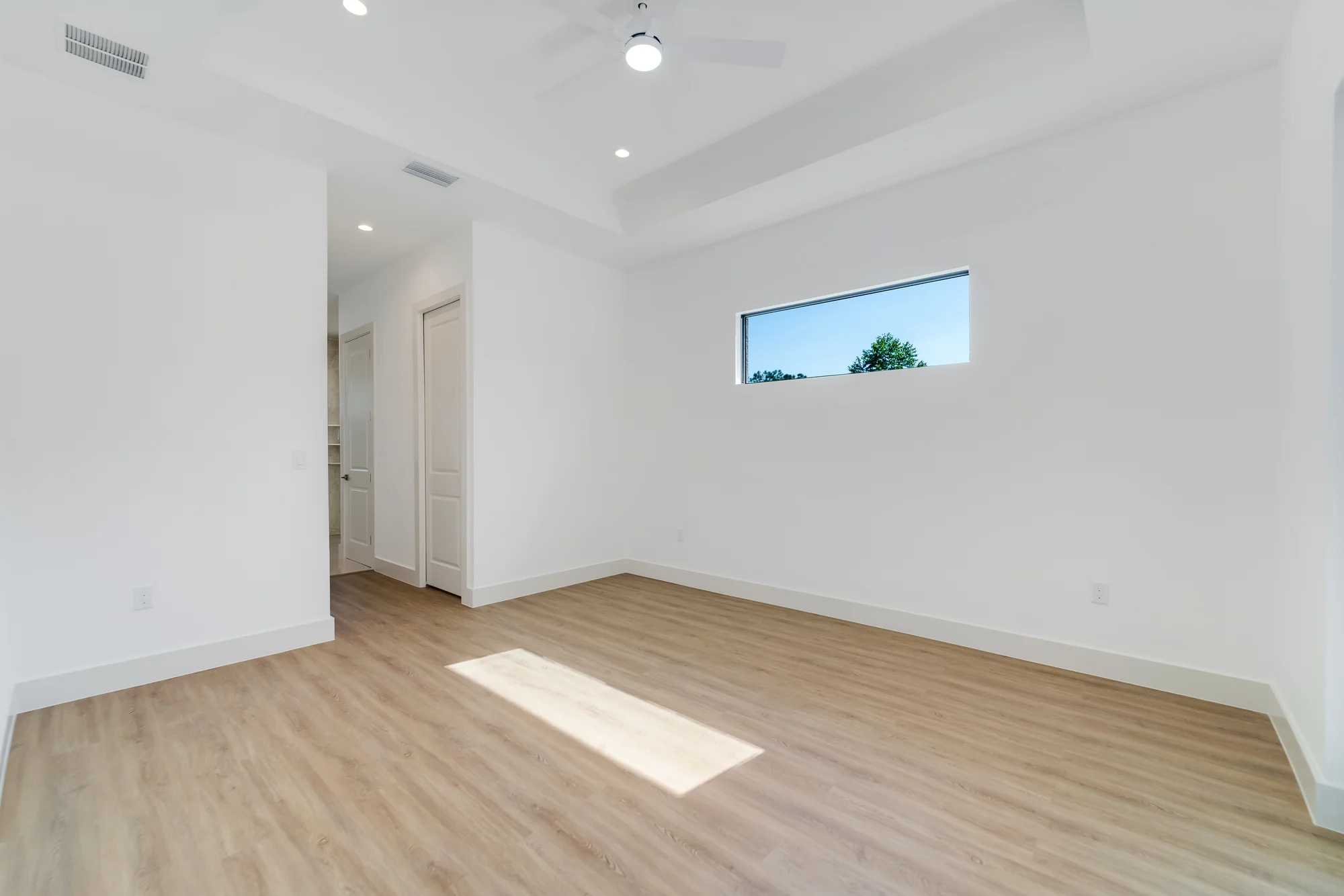 Spacious master suite with tray ceiling and custom millwork in The Sapphire contemporary waterfront home at 619 22nd St SE, Naples FL by XL Homes custom home builder