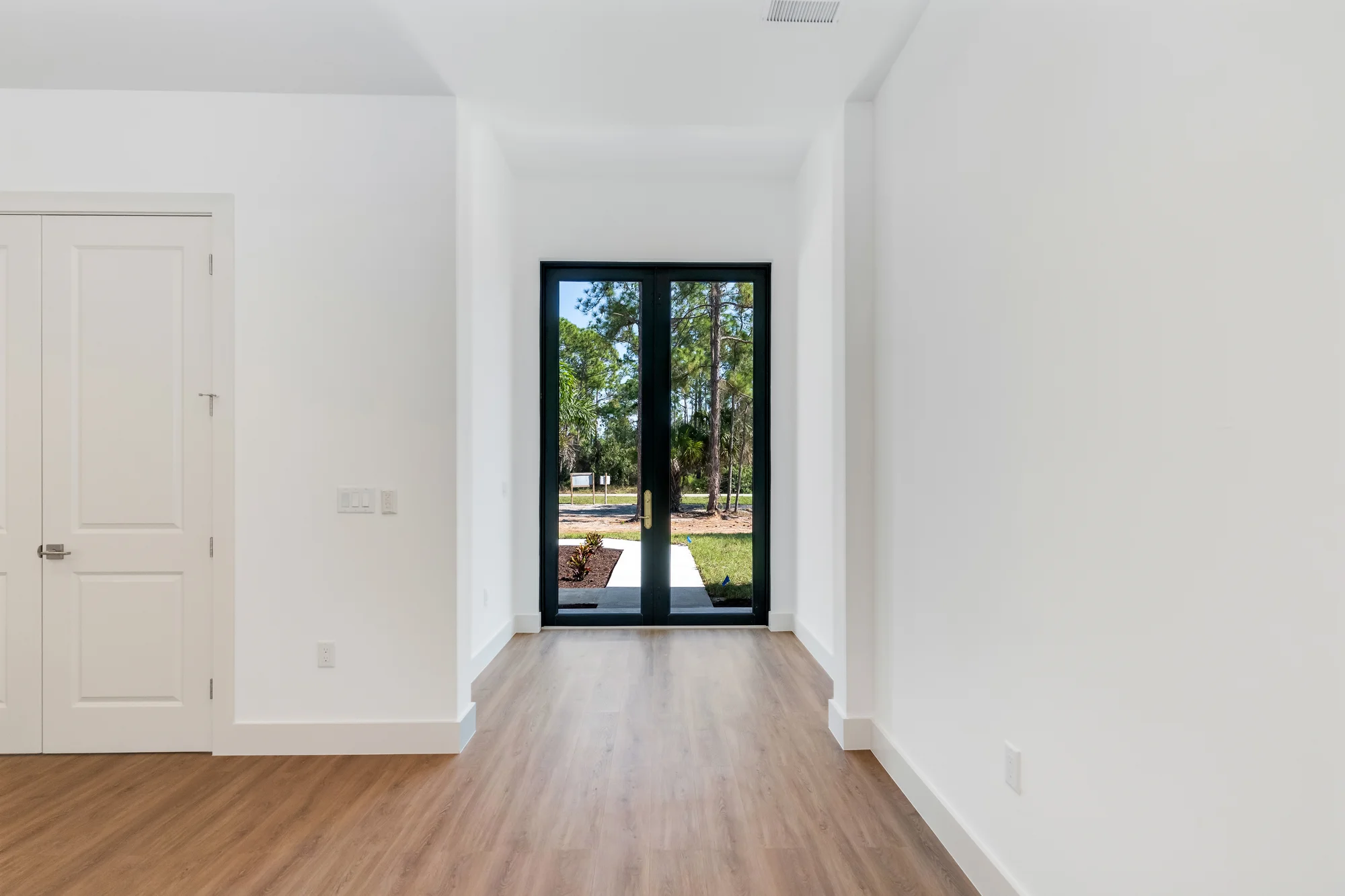 Grand entryway with statement door and decorative tile in The Sapphire contemporary waterfront home at 619 22nd St SE, Naples FL by XL Homes custom home builder