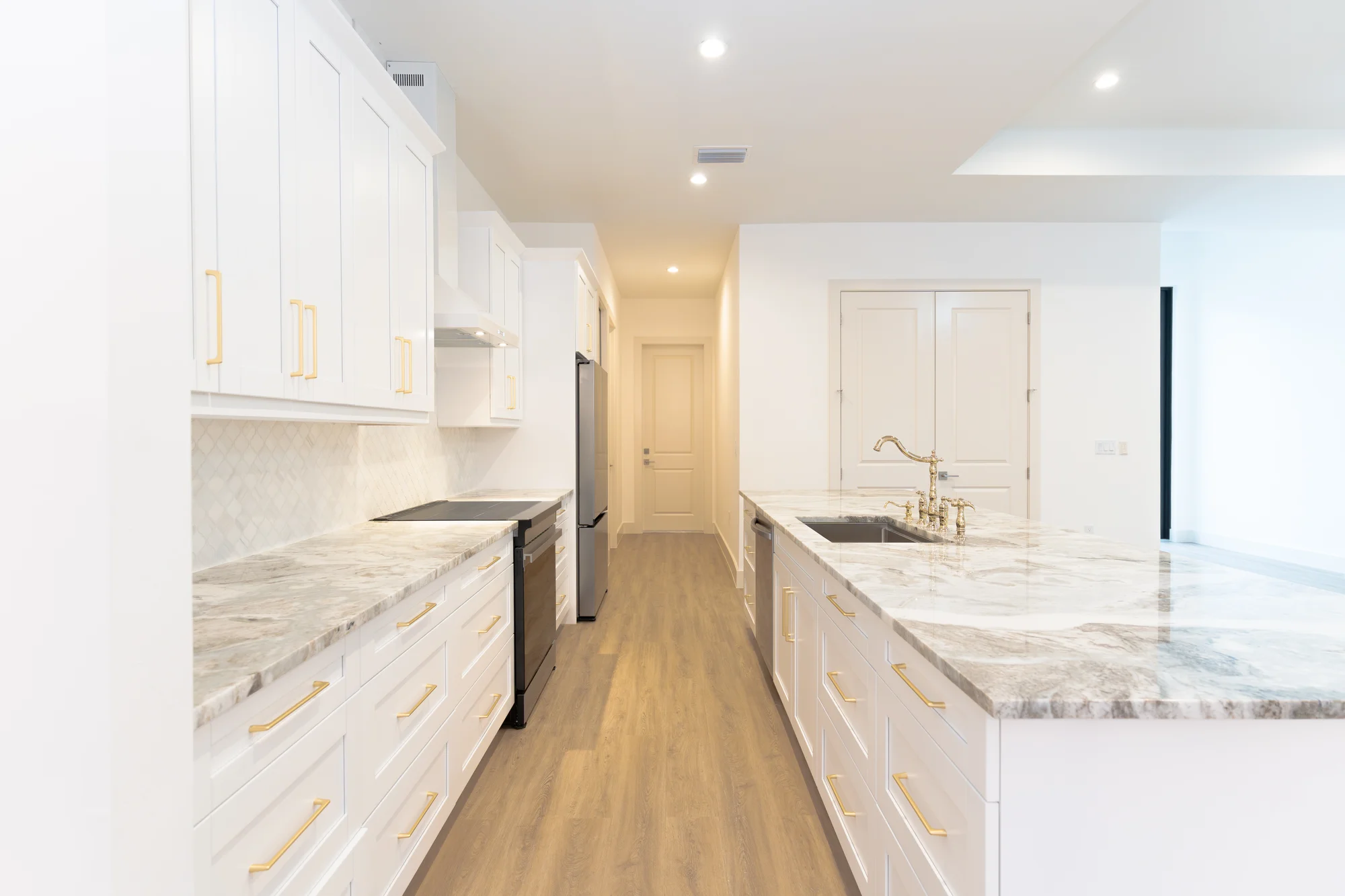 Elegant hallway with designer lighting and crown molding in The Sapphire contemporary waterfront home at 619 22nd St SE, Naples FL by XL Homes custom home builder