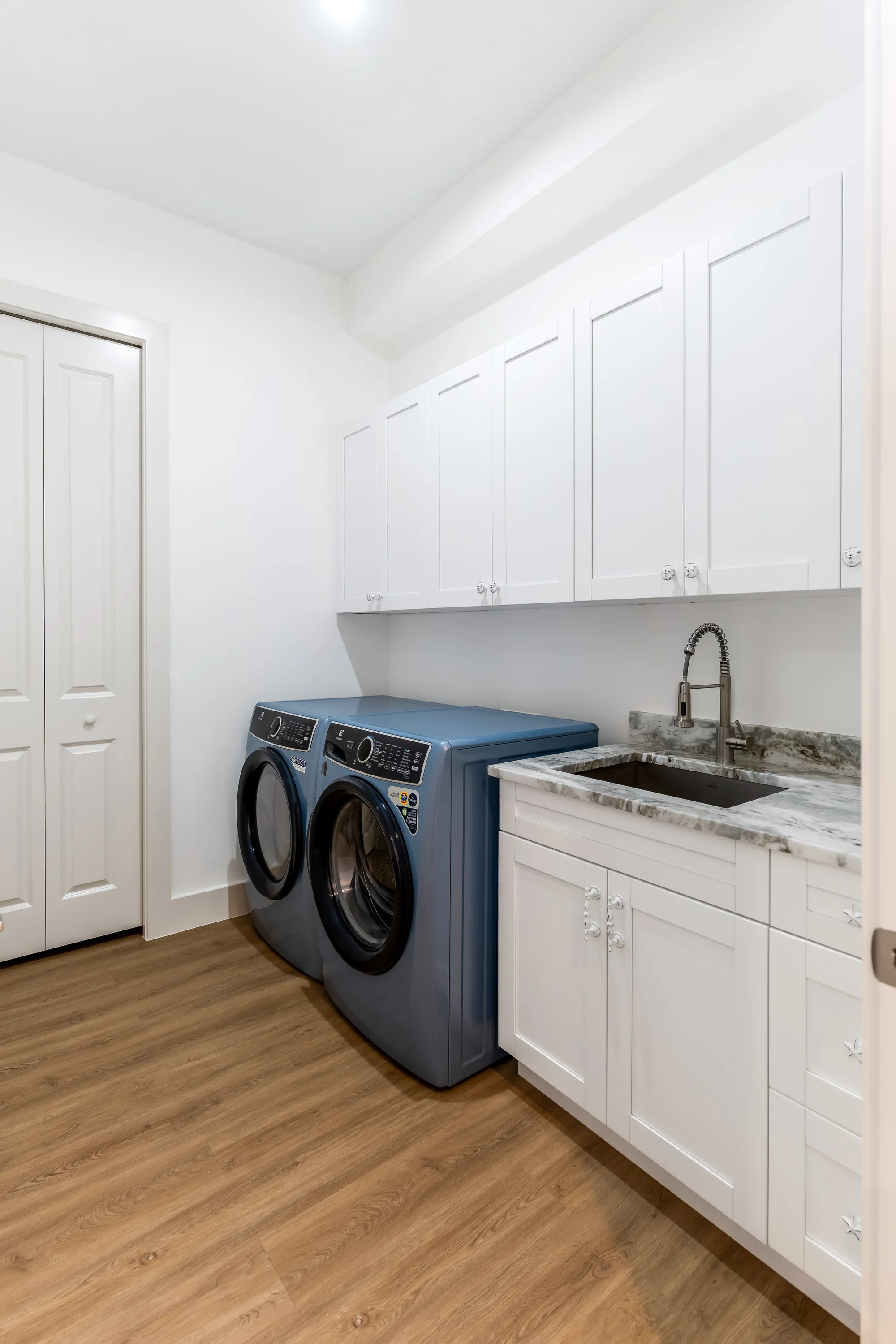 Premium laundry room with quartz countertops and cabinetry in The Sapphire contemporary waterfront home at 619 22nd St SE, Naples FL by XL Homes custom home builder