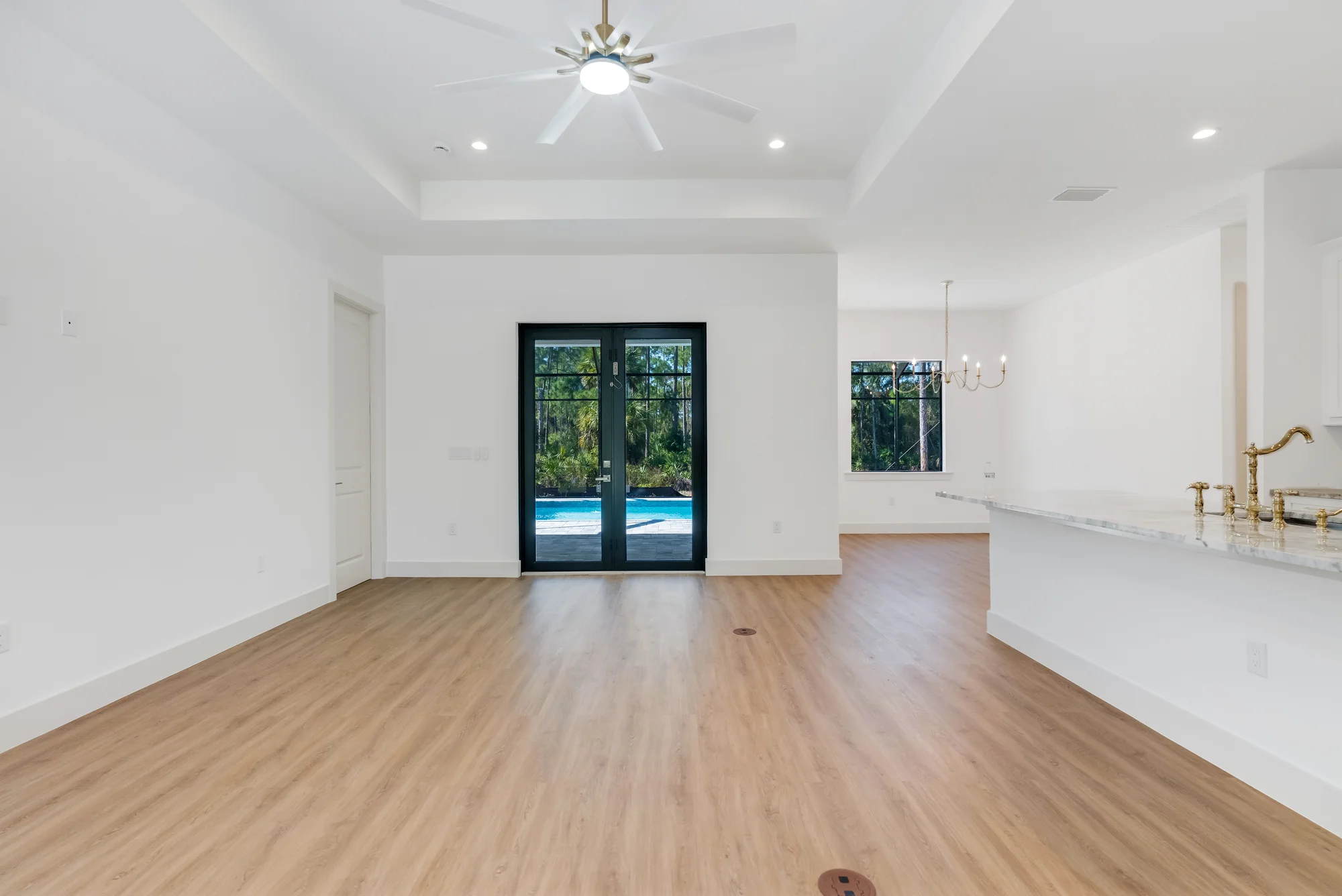 Open concept living room with high ceilings and natural light in The Sapphire contemporary waterfront home at 619 22nd St SE, Naples FL by XL Homes custom home builder